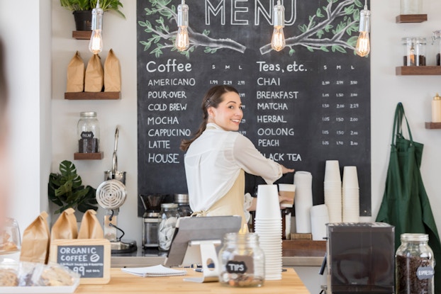 Woman working in a coffee shop making a cup of coffee.